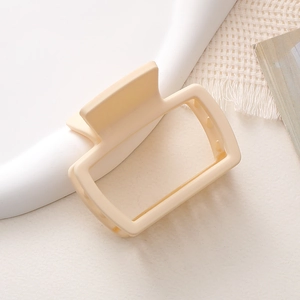 Dettaglio della pinza per capelli quadrata crema opaca su vassoio bianco