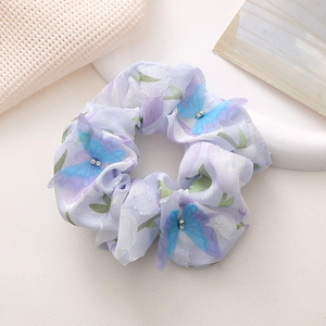 Detail eines lila Chiffon-Haargummis mit Organza-Schmetterling und Strasssteinen