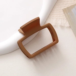 Dettaglio di una pinza per capelli rettangolare marrone opaco su vassoio ceramica