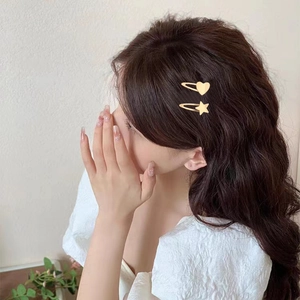 Barrettes dorées en forme d'étoile et de cœur sur cheveux bruns ondulés pour l'été