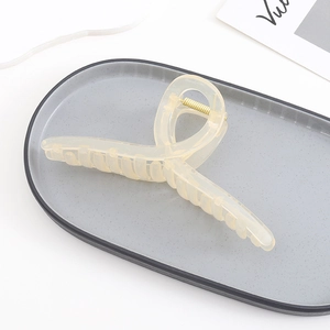 Detail of a large cream yellow translucent acrylic hair claw clip with golden metal spring