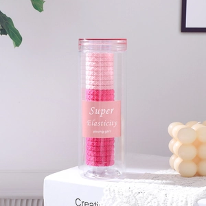 Élastiques à cheveux roses soigneusement rangés dans un bocal cylindrique transparent