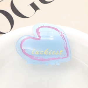 Pince à cheveux cœur en acétate bleu clair avec texte luckiest sur magazine de mode