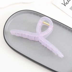 Macro detail of lavender acrylic hair claw clip with golden metal spring mechanism