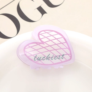 Détail d'une pince à cheveux cœur violette avec motif à carreaux rose et texte luckiest