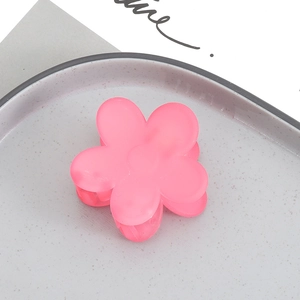 Detailed macro view of a matte pink flower-shaped hair claw clip on a gray tray