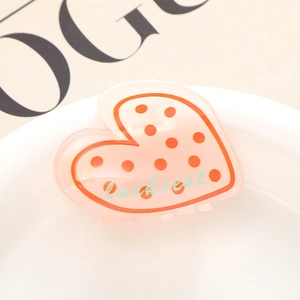 Gros plan sur la pince à cheveux cœur rose avec pois rouges et gravure luckiest