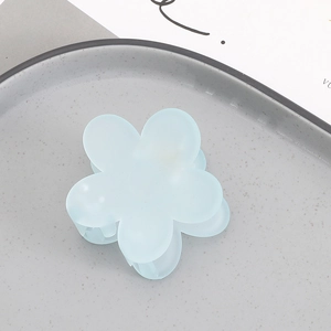 Detailed macro view of a light blue matte flower hair claw clip on a grey tray