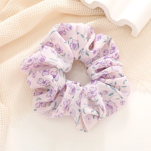 Close-up of pink floral scrunchie with soft purple flower prints on premium fabric