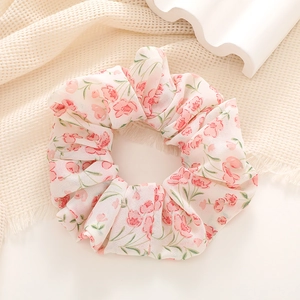 Close-up of floral print hair scrunchie with pink petals on soft chiffon fabric
