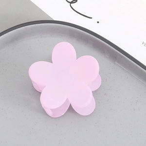 Close-up of a matte pale purple flower hair claw clip on a textured ceramic tray
