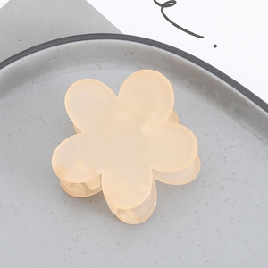 Close-up of matte floral hair claw clip in soft pink resin on a ceramic tray