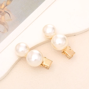 Detail of elegant gold-toned hair clips with lustrous white imitation pearls in pair