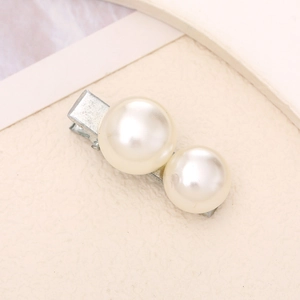 Detail view of a minimalist silver duckbill hair clip with two creamy white pearls