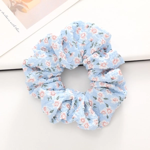 Détail du chouchou bleu clair à fleurs avec texture seersucker et ruban soyeux