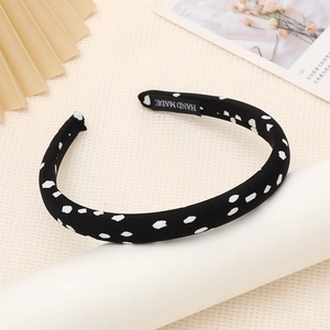 Detailed view of handmade black sponge headband with white polka dots and inner tag label