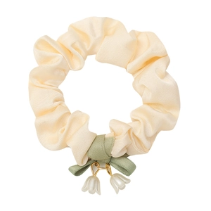 Scrunchie in raso crema con fiocco verde e ciondoli a forma di mughetto bianco