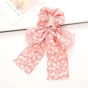 Détail d'un chouchou rose à fleurs avec de longs rubans en tissu gaufré élégant