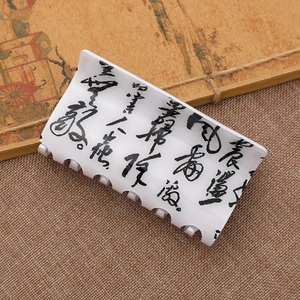 White claw clip with black ink calligraphy pattern on rustic brown linen background
