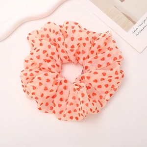 Close-up of a large chiffon scrunchie featuring a red heart pattern on light pink fabric