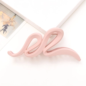 Détail d'une grande pince à cheveux rose mat ondulée avec un design profilé en forme de S