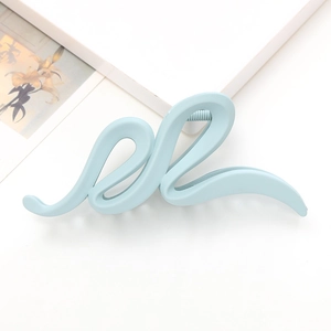 Détail d'une pince à cheveux mate bleu clair au design ondulé sur fond blanc minimaliste
