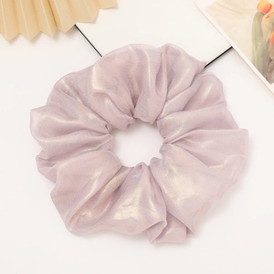 Detail of lavender scrunchie with metallic sheen and elegant pleats on white surface