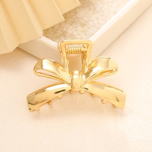 Elegant gold bow-shaped metal hair claw clip with a polished finish for half-up hairstyles