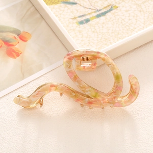 Elegant marbled acetate hair claw clip with golden metal spring on minimalist background