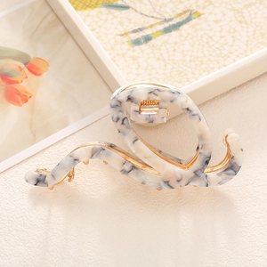 Detail of large acetate hair claw clip with grey marble texture and gold metal frame