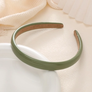 Close-up of dark green leather headband with brown suede non-slip inner lining on white plate