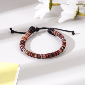 Close-up of ethnic woven bracelet with adjustable black cord and colorful geometric patterns