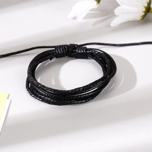 Detalle de pulsera de cuero trenzado negro de varias capas con cierre de nudo ajustable