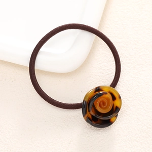 Detailed macro view of an elastic hair tie featuring a vintage amber resin rose decoration