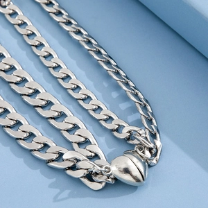 Detailed close-up of a silver curb chain with a heart-shaped magnetic clasp on blue background