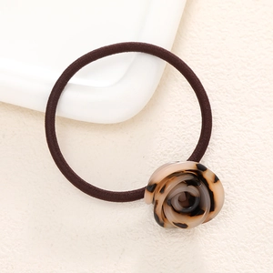 Detail view of tortoiseshell resin rose on a high-elasticity brown hair tie for women