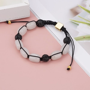 Detail of woven yoga bracelet with white crystal, black lava stones and gold metal clasp