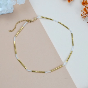 Minimalistische boho kralenketting met goudkleurige kralen en witte harsaccenten
