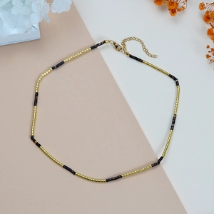 Minimalistische boheemse ketting met goud-bruine kralen op een platte achtergrond