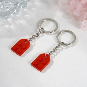Close-up of a pair of red building block keychains for couples with silver metal rings