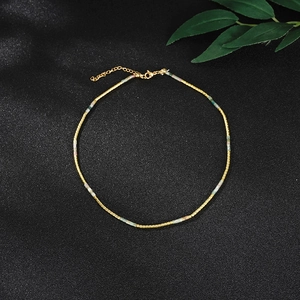 Detail van de kralenketting met gouden en groene kralen op zwarte achtergrond