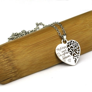Détail du collier cœur gravé Mother and Daughter forever sur support en bois