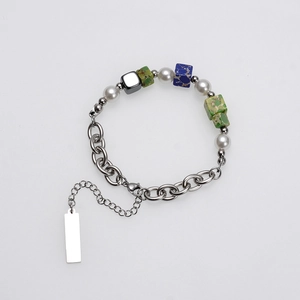 Detail van kralenarmband met witte parels, groene stenen en grove stalen schakelketting