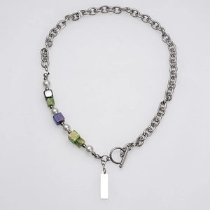 Detail van zilveren ketting met parels, natuurstenen en een strakke metalen hanger