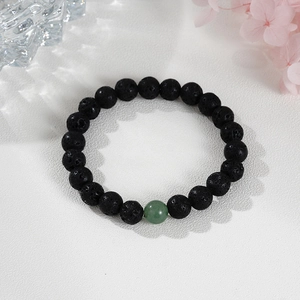 Minimalist beaded bracelet with black lava stones and a single green aventurine bead
