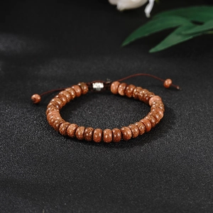 Macro detail of braided brown cord and shimmering goldstone beads on adjustable bracelet