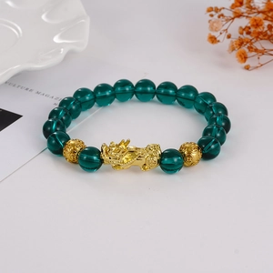 Deep green 8mm natural stone bracelet with golden Pi Xiu charm on white ceramic plate