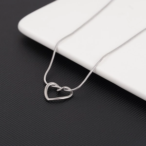 Détail du pendentif cœur creux minimaliste avec élégante chaîne serpent en argent contrasté