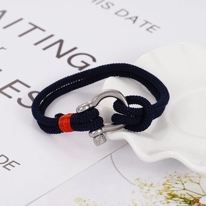 Detail eines blau geflochtenen Armbands mit silbernem Hufeisenverschluss und orangen Akzenten
