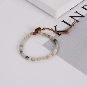 Bohemian natural stone beaded bracelet with woven cord closure on a minimalist background